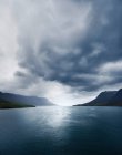 Cielo tormentoso sobre lago tranquilo y montañas - foto de stock