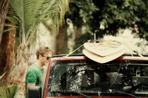 Чоловік зав'язує дошки для серфінгу на дах автомобіля — стокове фото