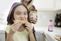 Girl eating sandwich and smiling — Stock Photo