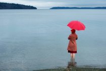 Mujer con paraguas en lago rural - foto de stock