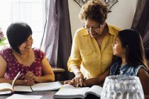 Mother and grandmother helping girl with homework — Stock Photo