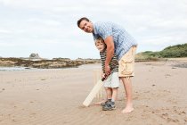 Pai e filho jogando críquete na praia — Fotografia de Stock