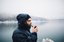 Vista lateral del hombre fumar pipa por lago, Bass Lake, California, EE.UU. - foto de stock