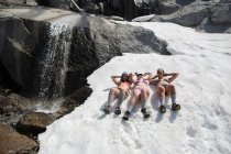 Três jovens mulheres vestindo biquínis, deitadas na neve, The Enchantments, Alpine Lakes Wilderness, Washington, EUA — Fotografia de Stock