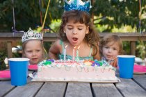 Mädchen pustet Kerzen auf Kuchen aus — Stockfoto