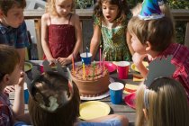 Kinder pusten Geburtstagskerzen aus — Stockfoto