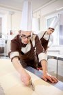 Пекарь режет тесто на кухне — стоковое фото