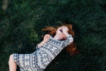 Високий кут зору дівчини, що лежить на траві, що покриває обличчя сміється — стокове фото