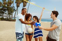 Friends on beach with volleyball and net — Stock Photo
