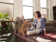 Mujer acariciando perro mascota en sala de estar - foto de stock