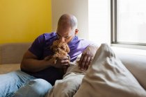 Mid adult male sitting on sofa with dog — Stock Photo