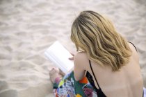 Woman reading book on beach — Stock Photo