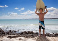 Portrait of young adult male surfer holding up surfboard — Stock Photo
