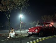 Woman sitting in car park at night — Stock Photo