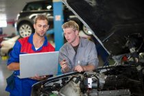 Kfz-Mechaniker diskutieren und analysieren Autoreparatur — Stockfoto
