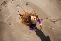 Молодые играют на песчаном пляже, сверху — стоковое фото