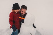 Отец и дочь делают снеговика — стоковое фото