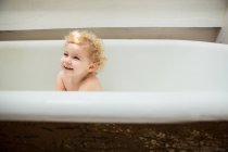 Criança sorridente sentada dentro da banheira — Fotografia de Stock