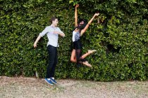 Jeune couple jouant dehors, sautant — Photo de stock