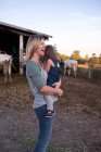 Mãe carregando filha na fazenda, mãe rindo — Fotografia de Stock