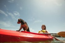 Adolescente chica y mascota perro en kayak - foto de stock