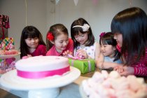 Menina desembrulhando presente de aniversário na festa — Fotografia de Stock