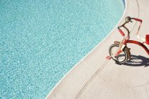 Triciclo bambino ai bordi della piscina — Foto stock