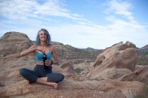 Donna seduta al Vazquez Rocks, aprendo una bottiglia con da bere — Foto stock