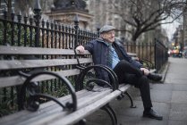Uomo seduto sulla panchina del parco sorridente, Manhattan, New York, USA — Foto stock