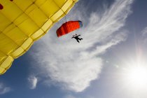 Female skydiver steering yellow parachute — Stock Photo