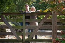 Casal inclinado no portão de madeira — Fotografia de Stock
