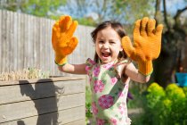 Young girl in garden wearing oversized gloves — Stock Photo