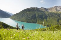 Young couple on mountain bikes looking out at Vernagt reservoir, Val Senales, South Tyrol, Italy — Stock Photo