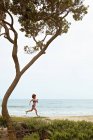 Jeune femme jogging sur la plage — Photo de stock
