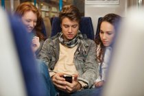 Tre giovani amici che viaggiano in treno ascoltando musica — Foto stock