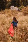 Young girl running through long grass, dragging sleeping bag, rear view, Mineral King, Sequoia National Park, California, USA — Stock Photo
