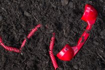 Rotes Retro-Telefon in Erde vergraben — Stockfoto