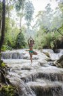 Frau steht auf einem Bein in Baumpose, im Kuang si Wasserfall, luang prabang, laos — Stockfoto