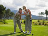 Мужчина дает женщине урок гольфа — стоковое фото