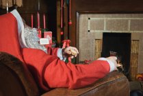 Père Noël se reposant près de la cheminée — Photo de stock