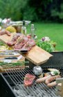 Cropped image of man putting steaks on barbecue grill in garden — Stock Photo