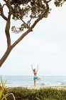 Junge Frau dehnt sich am Strand — Stockfoto