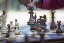 Hand moving chess piece on board, close up partial view — Stock Photo