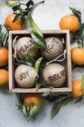 Top view of christmas decorations in wooden box surrounded by oranges — Stock Photo