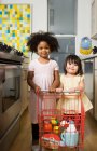 Mädchen schieben einen Spielzeug-Einkaufswagen — Stockfoto