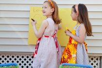 Girls making sign for selling homemade lemonade — Stock Photo