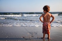 Niño mirando hacia el mar - foto de stock