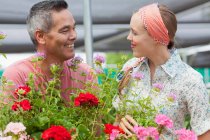 Зріла людина і середня доросла жінка купує в садовому центрі, посміхаючись — стокове фото