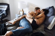 Männliches Paar, teilweise bekleidet, auf Bett liegend, küssend — Stockfoto