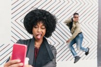 Woman taking selfie with friend in front of zig zag pattern wall — Stock Photo